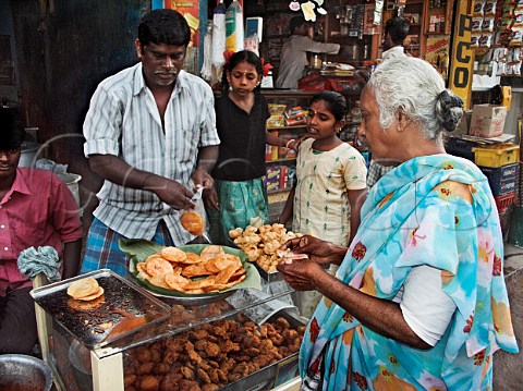 Indian woman buying deepfried Indian bread Wadai   made from wheat flour or rice flour Chennai   Madras India