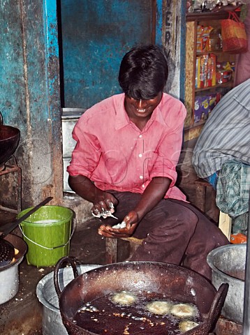 Indian man preparing and cooking deepfried Indian   bread Wadai made from wheat flour or rice flour   Chennai Madras India