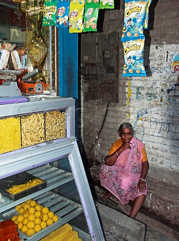 Indian woman sat in shade by Anjali Sweet shop    Palavakkam Chennai Madras India
