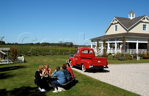Visitors drinking wine with lunch by red pickup truck in car park of Bedell Cellars Cutchogue Long Island New York USA
