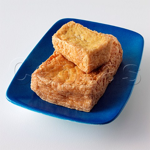 A blue dish with two pieces of tofu