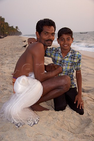 Young boy with his fisherman father on the beach at Kattoor Kalavoor Alappuzha Alleppey Kerala India