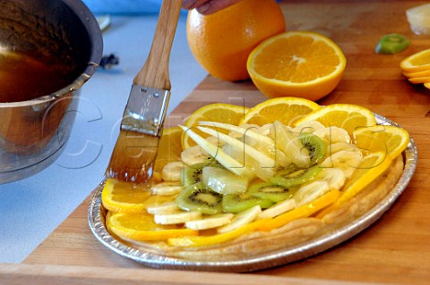 Brushing syrup glaze on a fresh fruit tart