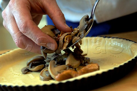 Making a mushroom quiche putting mushrooms on the pastry base