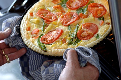 Taking a vegetable quiche out of the oven