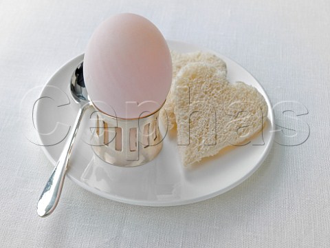 White egg in a cup and heart shaped bread