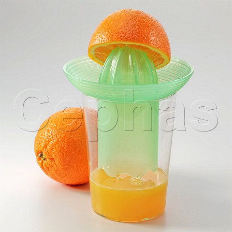 Half an orange on a juicer with orange juice on a white background