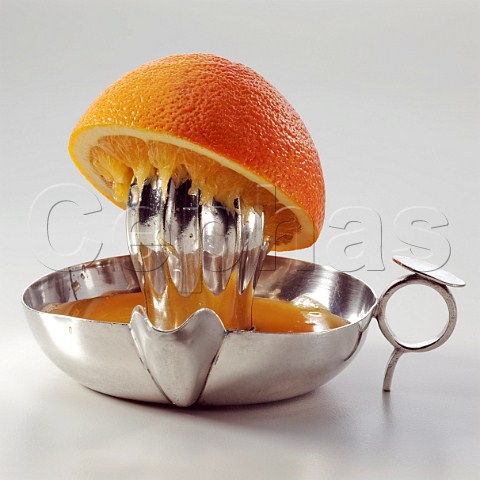 Half an orange on a metal juicer on a white background