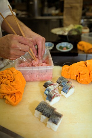 Adding pink ginger to mackerel sushi in a Japanese restaurant
