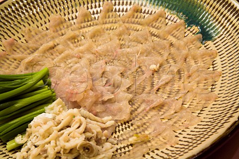 Plate of freshly prepared fugu blowfish sashimi with spring onions