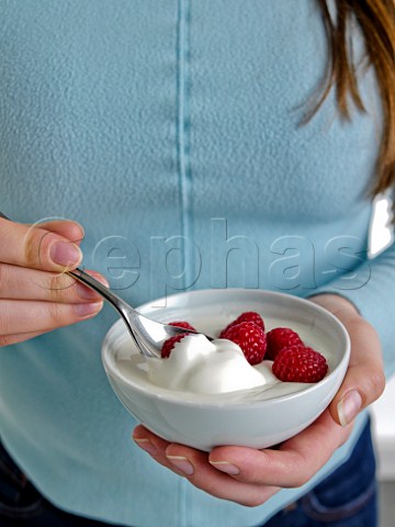 Woman eating raspberries and yoghurt