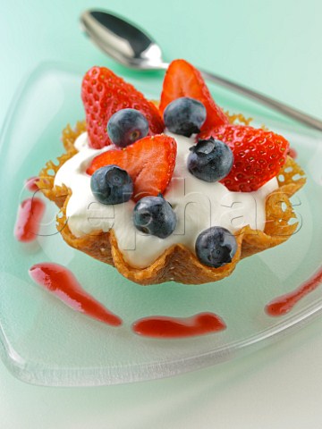 Strawberries and blueberries with cream in a brandysnap basket