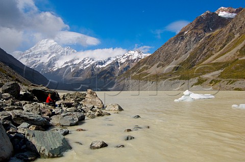 Walker on the shore of the glacier fed Hooker Lake with Mt Cook in background Hooker Valley Mt CookAoraki National Park South Island New Zealand