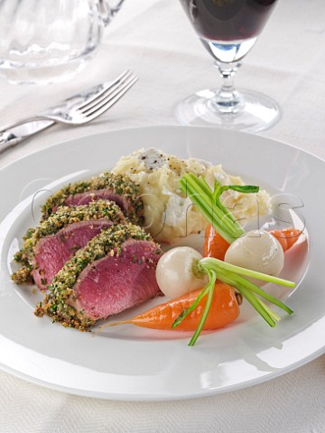 Plate of lamb loin in a herb crust with vegetables