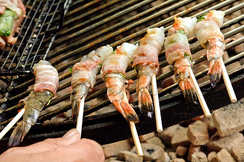 Barbecueing prawns wrapped in bacon