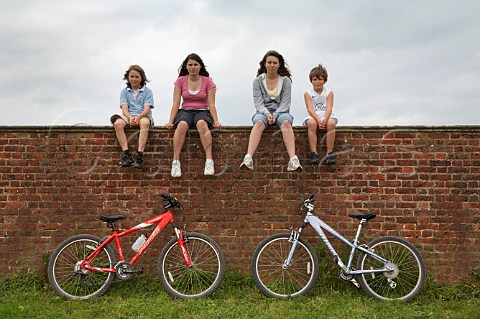 Family group two sisters and two brothers sitting on wall with two mountain bikes