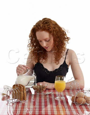 Young woman sitting at breakfast table bran flakes and milk wholemeal toast boiled eggs orange juice