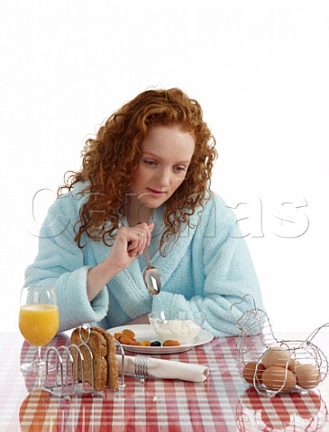 Young woman sitting at breakfast table yoghurt with dried fruits wholemeal toast boiled eggs orange juice