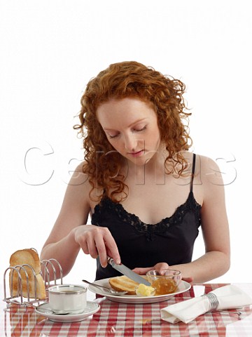 Young woman at breakfast table toast and marmalade cup of black coffee
