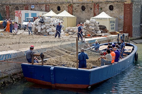 Fishermen preparing fishing nets in Favignana harbour Favignana Island Sicily Italy
