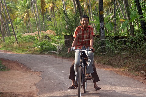 Two Indian boys ride on a bicycle Costa Malabari near Kannur Cannanore on the CochinMysore  CochinGoa route North Kerala India