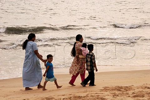 Indian family walking along Costa Malabari beach near Kannur Cannanore on the CochinMysore  CochinGoa route North Kerala India