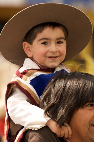 Young boy dressed as a Huaso on his fathers shoulders  18th September Independence Day celebration Santa Cruz Chile