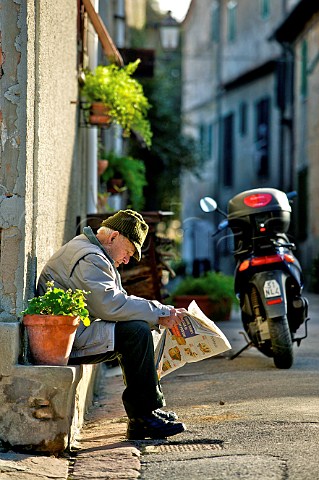 Old man reading newspaper in the village of Bolgheri Tuscany Italy Bolgheri