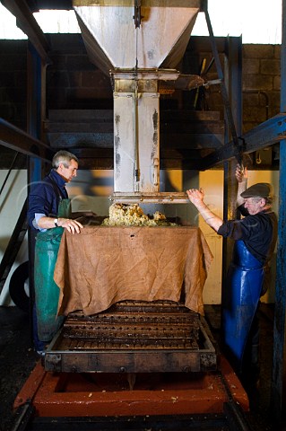 Artisan cider maker Roger Wilkins right building a cheese of crushed apples for pressing on his hydraulic Beare press  Wilkins Cider Landsend Farm Mudgley Wedmore Somerset England