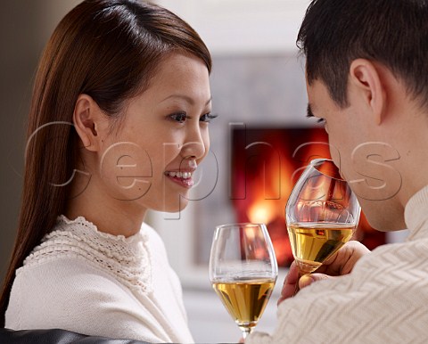 Young oriental couple drinking wine at home