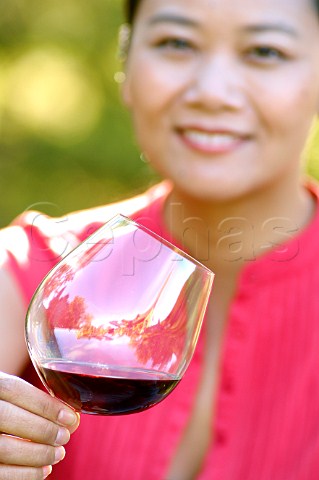 Oriental woman drinking red wine in a vineyard