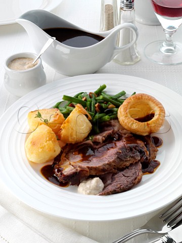 A plate of sliced boned roast rib of beef in a table setting