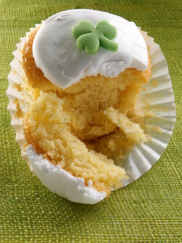 Cupcake with a green shamrock on top of the white icing broken open