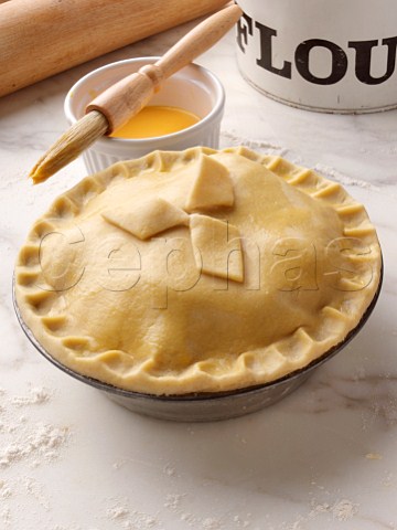 Shortcrust pastry pie in a pie tin brushed with egg yolk