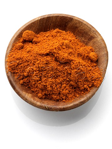 Chili powder in a wooden bowl on a white background