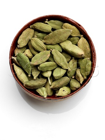 A bowl of green cardamoms on a white background