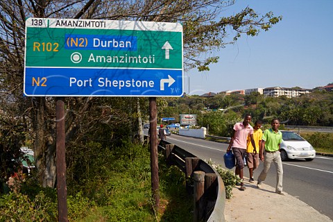 Boys walking past road sign at Amanzimtoti KwaZuluNatal South Africa