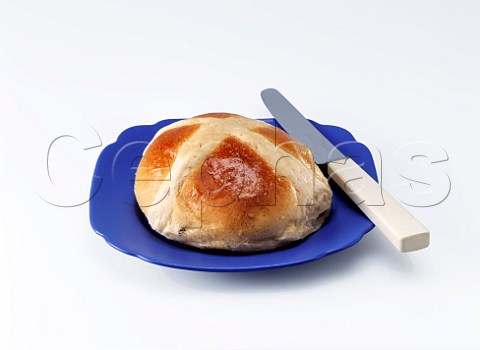 Easter hot cross bun on a blue plate on a white background