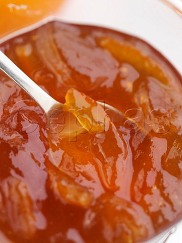 A glass jar of home made marmalade with a spoon