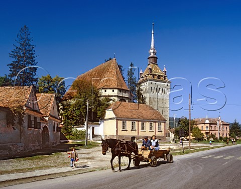 Traditional horsedrawn cart passing the fortified church at Saschiz Transylvania Romania