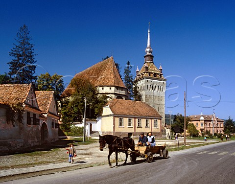 Traditional horsedrawn wagon passing church at Saschiz Transylvania Romania