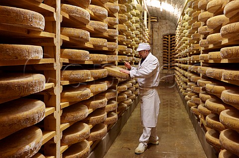 Mr Claude Querry tapping with a small hammer to check quality and development of Grand Cru Comt cheeses at least 18 months old in the cellars of Fromageries Marcel Petite 100000 wheels age here at any one time Fort Saint Antoine near Malbuisson Doubs France