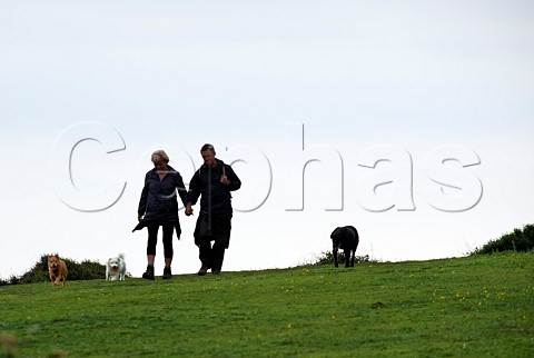 Couple walking with three dogs Seaford Head Sussex England