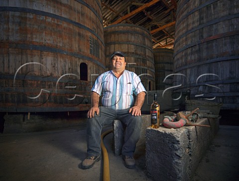 Don Luis head distiller in the aging room with a bottle of his goldmedal winning Pisco Chanaral Caren pisco distillery Limari Valley Chile