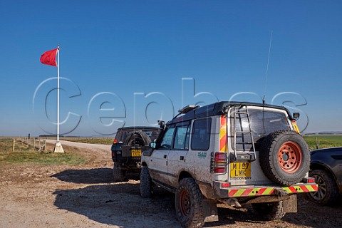 Red flag flying to warn of danger from military live firing with offroad vehicles on Public Byway Salisbury Plain Wiltshire England