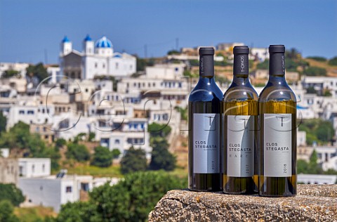 Three bottles of TOinos Clos Stegasta wines Assyrtiko and Mavrotragano with village of Falatados beyond Tinos Greece
