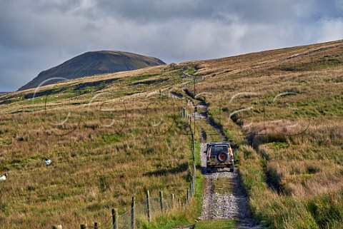 Car on unsurfaced road near Helwith Bridge with summit of Pen y Ghent in distance Yorkshire Dales National Park England