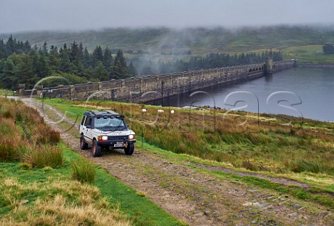 Car on unsurfaced road by Scar House Reservoir Dam Yorkshire Dales National Park England