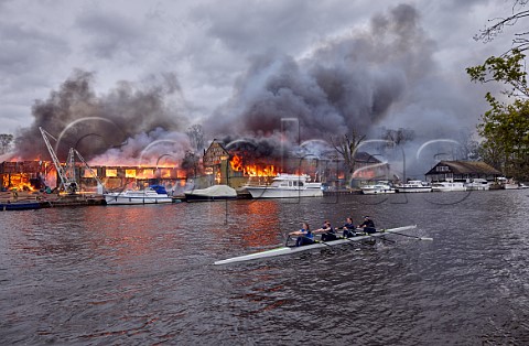 Rowers from Wimbledon High School passing the Platts Eyot fire of 3 May 2021 which destroyed the boat shed of Otter Marine and the Dunkirk evacuation ship Lady Gay The River Thames at Hampton Middlesex England