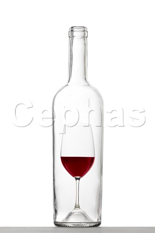 Bottle with glass of red wine inside